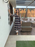 Woman in a patterned dress standing in an outdoor patio area.