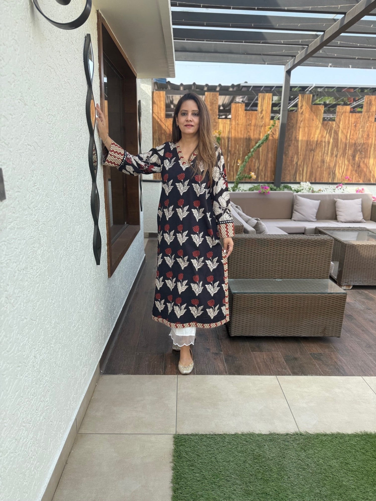 Woman in a patterned dress standing in an outdoor patio area.